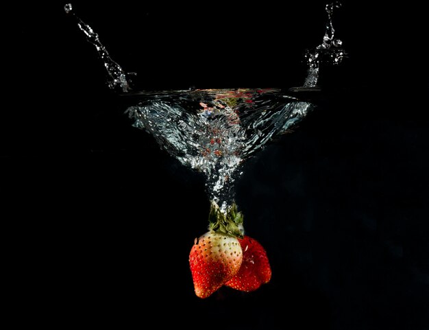 Photo close-up of strawberries in water against black background