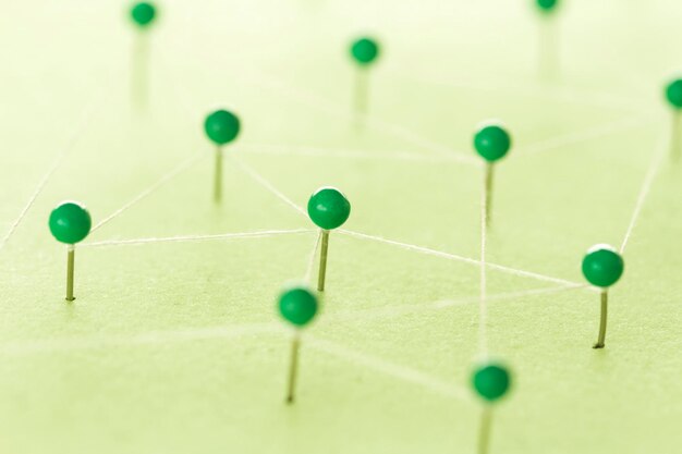 Близкий план струн, соединенных зелеными прямыми булавками на столе