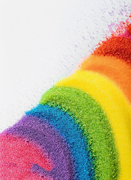 Close up of stripes of rainbow coloured sand and copy space on white background