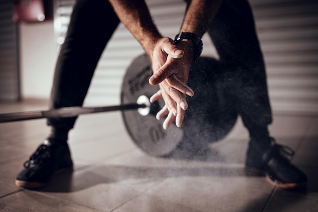 Close-up of a strong man's hands with talc getting ready to weightlifting at the garage gym.