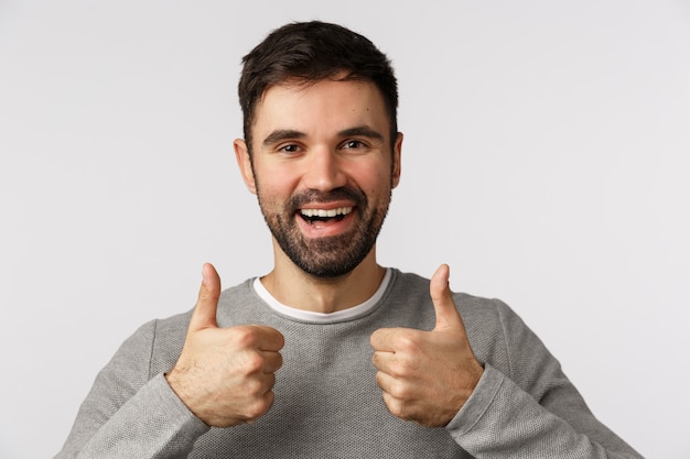 Close-up studio pleased, satisfied good-looking bearded male friend show thumbs-up in approval