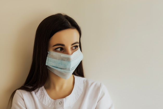 Close up studio portrait of woman wearing face medical mask, looking away