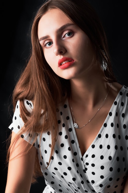 Close-up studio portret van een jong meisje met lang haar en rode lippen tegen zwart.