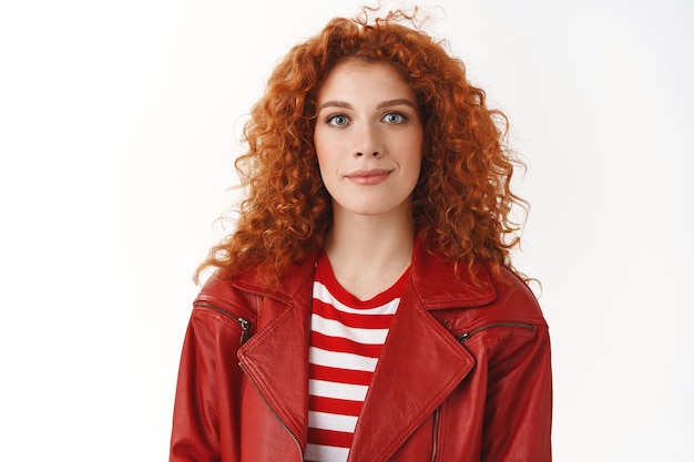 Close-up stylish good-looking redhead millennial girl waiting queue make order take-away head work look trendy wearing red leather jacket make-up smiling delighted standing happy white wall
