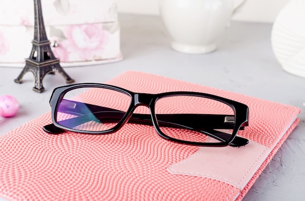 Close Up Stylish womens black eyeglass on pink notebook,