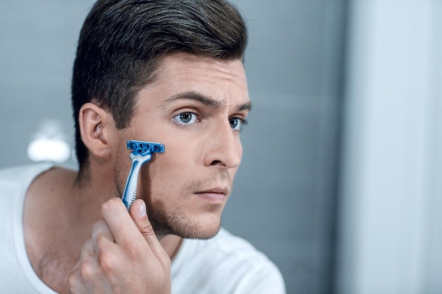 Close up stylish young man shaves his facethe concept of personal hygiene