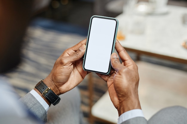 Foto primo piano di un uomo d'affari afroamericano di successo che tiene in mano uno smartphone con schermo vuoto, copia spazio