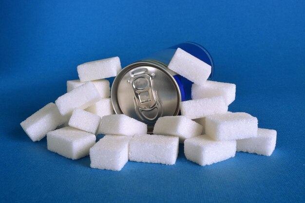 Photo close-up of sugar cube with drink can over blue background