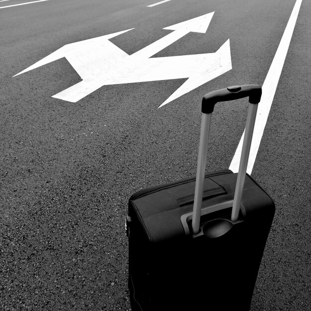 Close-up of suitcase by arrow symbol on road