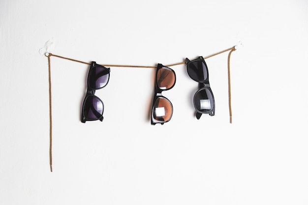 Photo close-up of sunglasses hanging on string over wall