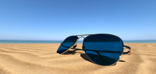 Крупным планом солнцезащитные очки на песчаном пляже
