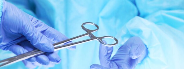 Close-up of of surgeons hands at work in operating theater toned in blue. Medical team performing operation