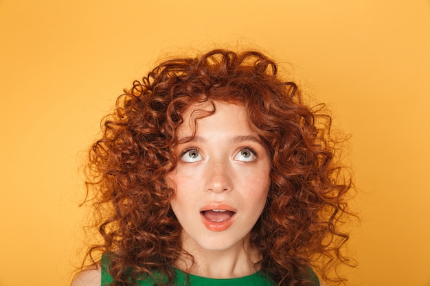 Close up of surprised young curly redhead woman