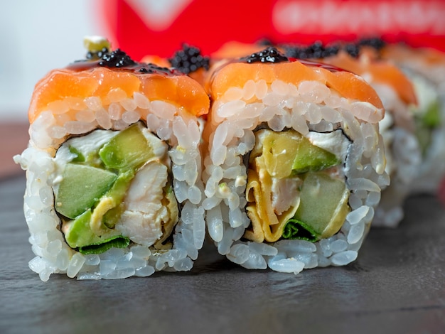 Close-up of a sushi roll on a black plate. Traditional Japanese cuisine