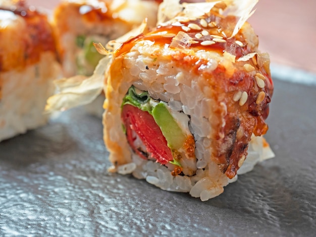 Close-up of a sushi roll on a black plate. Traditional Japanese cuisine