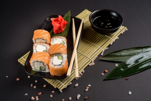Close up sushi rolls in a black plate on dark background