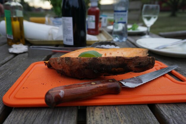 Photo close-up of sweet potato with knife on cutting board