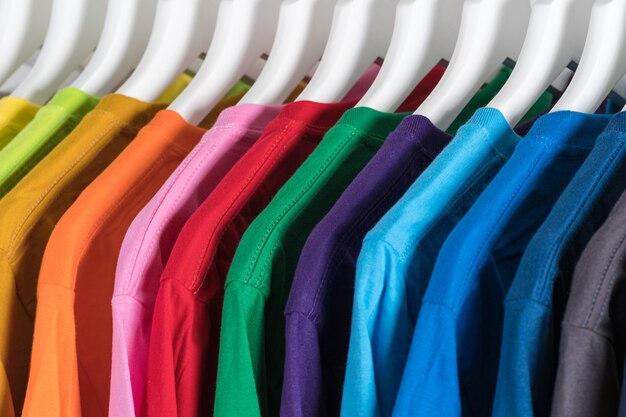 Photo close up of t-shirts, clothes on hangers on white background