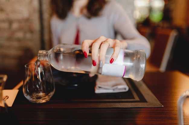 Close-up tabel instelling in restaurant. onherkenbaar vrouw hand met een fles vers water gieten in het glas.