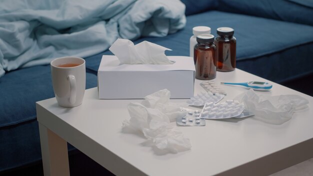Close up of table with tissues medication and tea in emtpy space