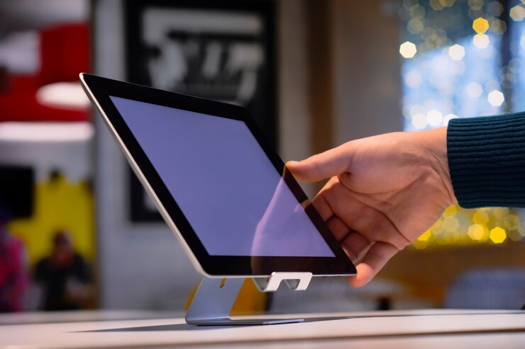 Close-up Tablet with white screen on the table. A male freelancer works in a cafe.