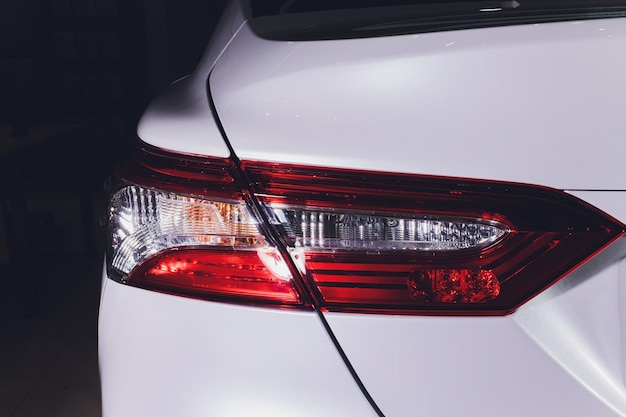 Close up of taillight detail of modern luxury sports car with reflection on white paint after wash wax. Rear view of supercar break lights. Concept of car detailing and paint protection