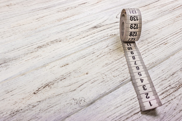 Close up tailor measuring tape on wooden table.