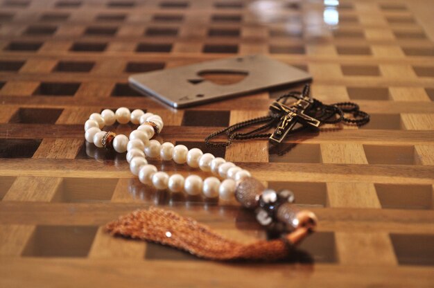 Photo close-up of tasbih and rosary on floor