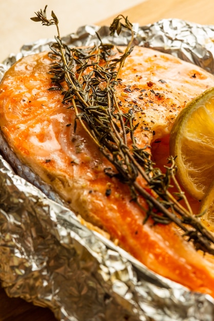 Close up of the tasty baked fish in foil with herbs and a branch of thyme on the top