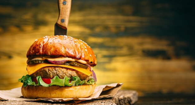 Chiudere un gustoso hamburger di manzo su un tavolo di legno con un coltello inserito dentro