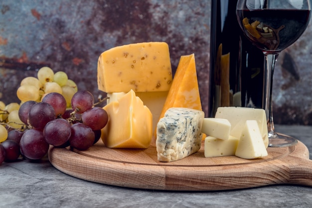 Photo close-up tasty cheese selection with wine and grapes