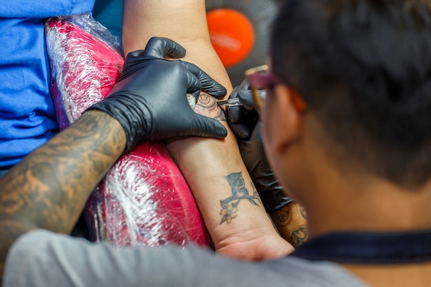 Close-up tattoo artiest toont het proces van het krijgen van zwarte tatoeage met verf. master werkt in zwart-steriele handschoenen.
