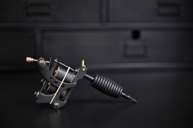 Close up of tattoo machine on dark metallic background. Space for text.