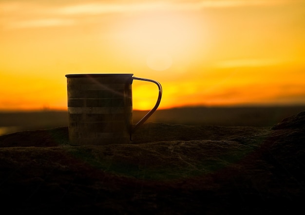 Close-up of tea against orange sky during sunset