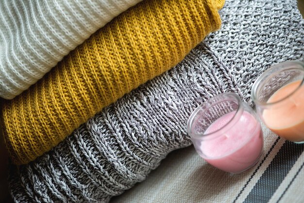 Photo close-up of tea light candles by stacked sweaters on table