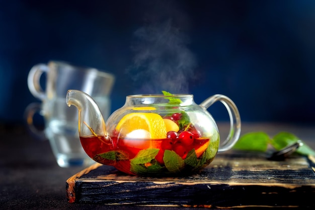 Close up of tea pot with hot fruit tea against dark blue background