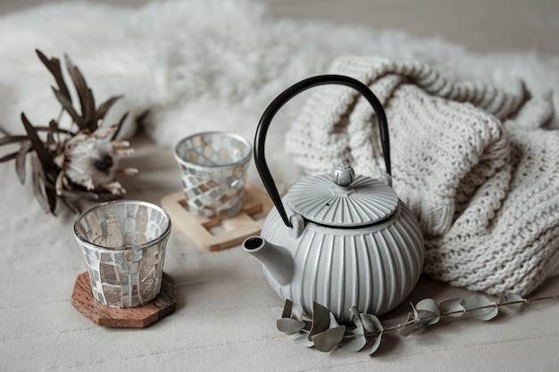 Close-up of teapot in scandinavian style with tea with knitted element and decor details