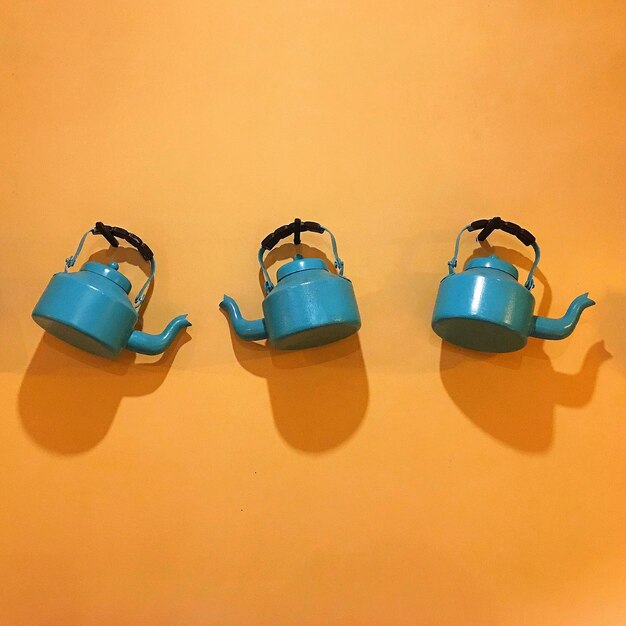 Photo close-up of teapots on orange wall