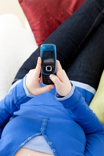 Close-up of a teen girl sending a text lying on a sofa 