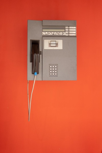 Close-up of telephone booth against orange wall