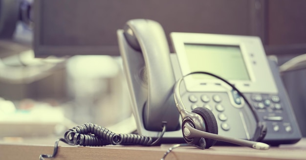 Photo close-up of telephone and headset on table