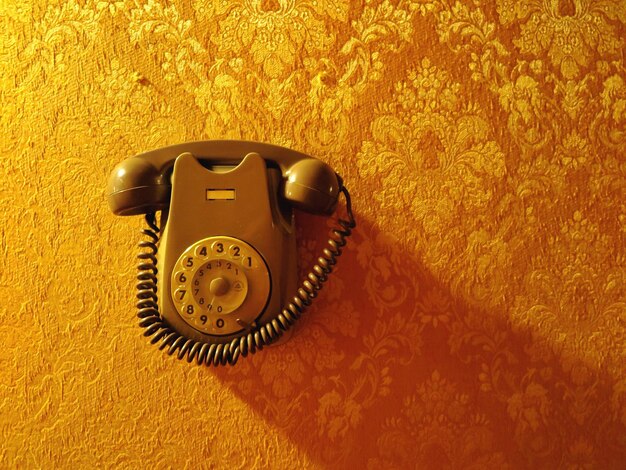 Photo close-up of telephone over yellow wall