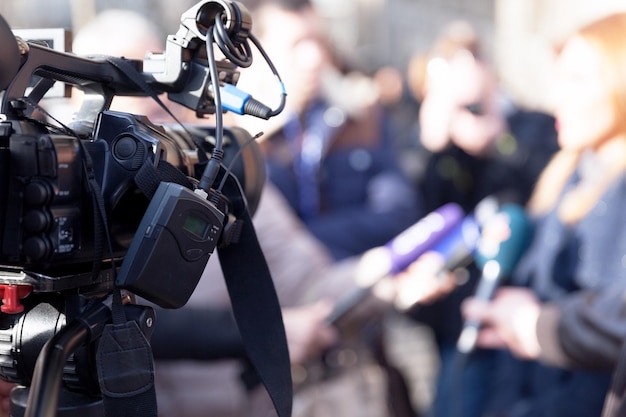 Photo close-up of television camera with people in background