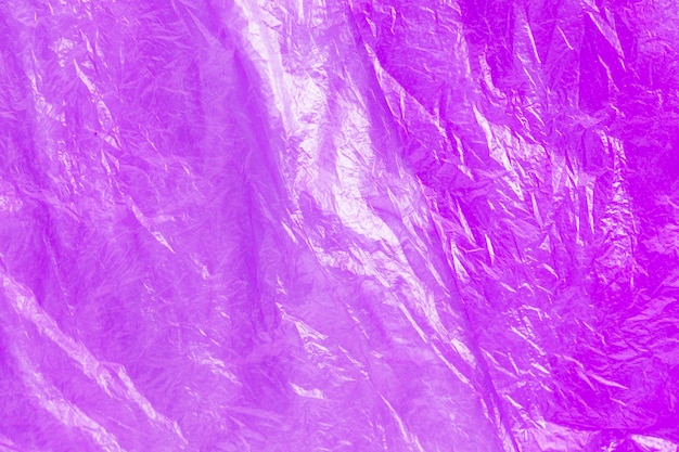 Close up texture of bright purple plastic garbage bag. Crumpled cellophane. Violet polyethylene film background. Ecology problem.