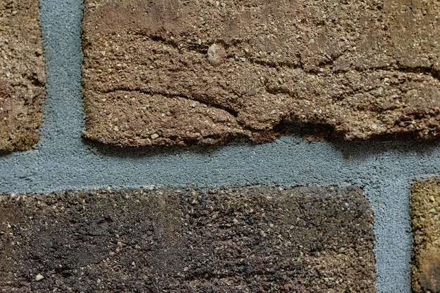 Close-up texture of a brown scratched brick wall with a gray seam