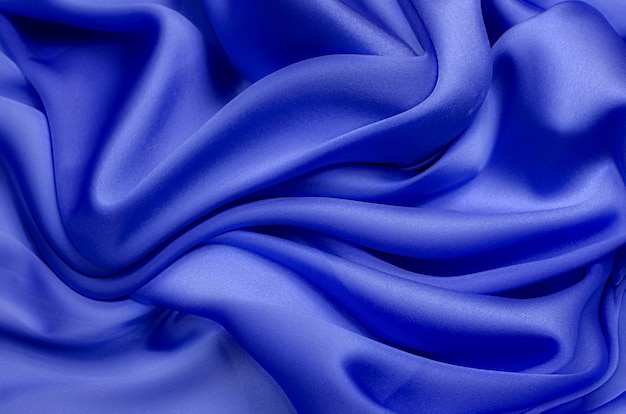 Close-up texture of natural blue fabric or cloth in same color. Fabric texture of natural cotton or silk or wool textile material. Blue canvas background.