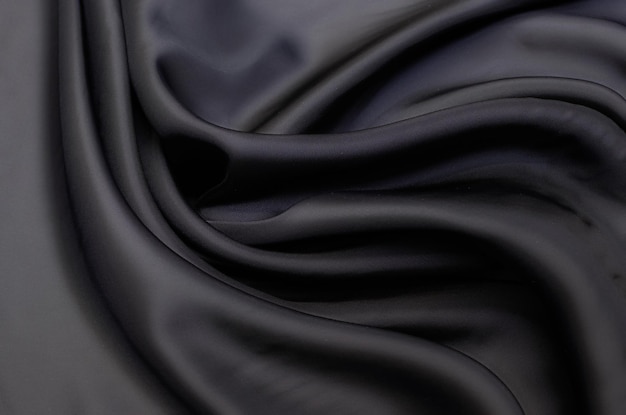 Close-up texture of natural gray or black fabric or cloth in same color. Fabric texture of natural cotton, silk or wool, or linen textile material. Black canvas background.