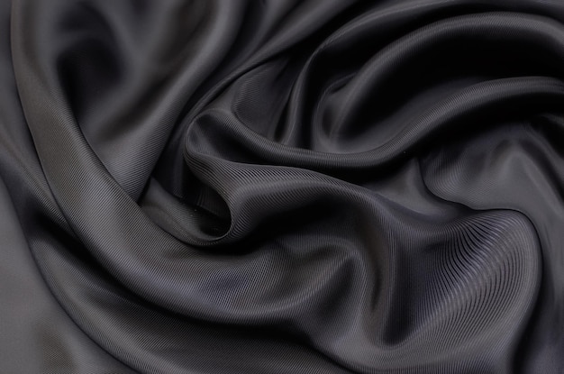 Close-up texture of natural gray or black fabric or cloth in same color. Fabric texture of natural cotton, silk or wool, or linen textile material. Black canvas background.