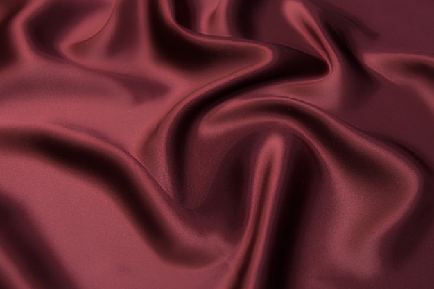 Close-up texture of natural red or burgundy fabric or cloth in same color. Fabric texture of natural cotton, silk or wool, or linen textile material. Red canvas background.