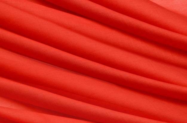 Close-up texture of natural red or crimson or pink  fabric. Fabric texture of natural cotton, silk or wool, or linen textile material. Red and orange canvas background.